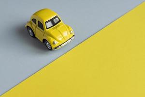 Flat lay in a trendy 2021 new colors. Illuminating Yellow and Ultimate Gray. Color of the Year 2021. Retro toy car on grey background with copy sapce. photo