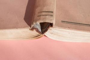 Open hardcover old book on pink background with copy space. Educational concept photo