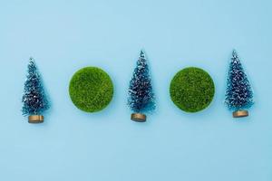 mini christmas trees and green balls on blue background. Christmas and New Year holiday concept. winter festive season. flat lay. copy space photo