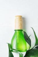 botella cosmética natural para el cuidado de la piel con pipeta y hoja verde orgánica sobre fondo blanco. remedio casero y concepto de producto de belleza. foto