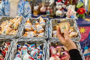 mano femenina sosteniendo en la tienda un adorno de juguete, decoración navideña. preparación para las vacaciones foto