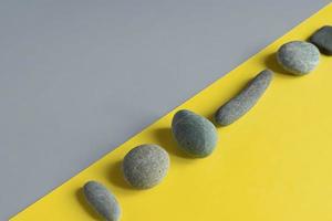 Flat lay in a trendy 2021 new colors. Illuminating Yellow and Ultimate Gray. Color of the Year 2021. Grey sea stones on yellow background. photo