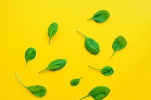 Food background of spinach leavs on yelow background photo