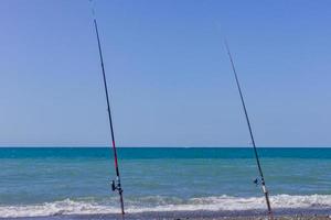 dos cañas de pescar en la playa del mar. turismo de pesca y concepto de vacaciones foto