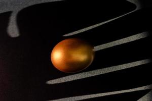 Golden egg on black background . Minimal style backdrop with copy space. photo