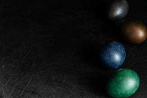 huevos de Pascua pintados de mármol de colores sobre fondo negro. concepto de fondo festivo mínimo de pascua foto
