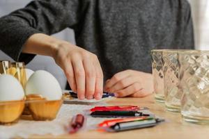 niño pequeño coloreando huevos para pascua. pascua, familia, concepto de vacaciones foto