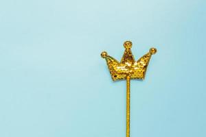 golden magic stick from sequins in crown shape on pastel blue background. Creative flat lay in minimal style photo