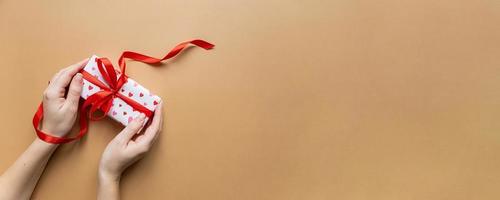 Top view of female hands holding present box package over flat lay background, Banner photo