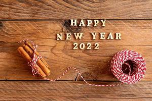 happy new year quotation made with wooden letters decorated with cinnamin sticks and red and white cord. Festive new year background photo