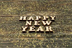 Happy New Year 2021. Symbol made from wooden letters and numbers 2021 on wooden background with golden confetti photo