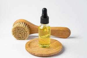 cuentagotas de botella de aceite esencial. spa, masajes y aromaterapia. cepillos de masaje, aceite en botellas de vidrio sobre fondo blanco foto