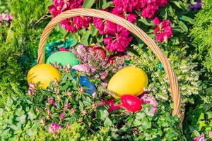 Easter street decoration. Wicker basket full of painted easter eeggs, cake and flowers. photo