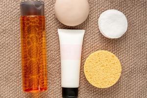 Face care concept. Cream, soap bar, sponge, cotton pads and losion on a towel. photo