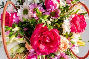 Beautiful spring bouquet in a paper basket with handles. Arrangement with various flowers. The concept of a flower shop. Work florist. photo