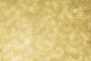 Abstract defocused background texture with golden sparkling glitter. Festive blurred backdrop for greeting cards and other design photo