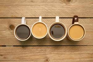 Many cups with tasty aromatic coffee on wooden table. Top view with copy space photo