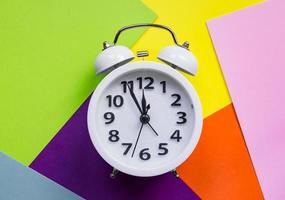 Flat lay white new alarm clock on bright multicolored background. photo