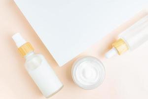 Concept skin care. A set of cosmetic products, creams and serum. Frosted glass bottles on white podium and beige background. Rejuvenation and moisturizing. Flat lay. Top view photo