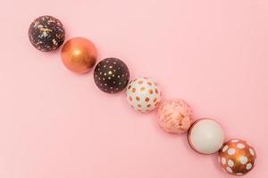 Pink background with colorful easter eggs in a row painted in gold, white and black colors. Creative layout with copy space photo