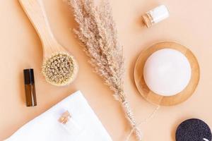 Spa and wellness concept with sea salt, dry pampas, face brush, oil and face sponges on beige background, top view. Eco friendly organic face care accesories photo