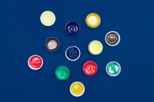 Top view of open acrylic paint cans. Colorful paints on blue background. photo