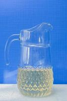 Glass jar with fresh lemonade on blue background. Summer refreshment. photo