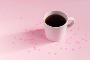 Pink cup of teea on pink background ith hearts. Love and care concept. Minimal style photo