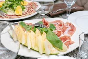 jamón prosciutto di parma con melón servido en un plato blanco en el restaurante foto