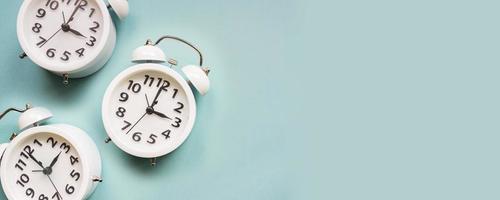 Flat lay white beautiful new alarm clock on blue color background. Pattern. Copy space photo