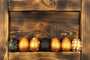 Easter festive background. Top view of easter eggs colored with golden paint on dark wood background. Various dotted design photo