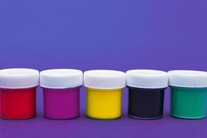 Large set of acrylic paint cans in a row. Colorful paints neon blue and violet background with copyspace. photo