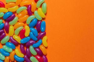 Assorted Jelly Beans border with copyspace on orange background photo