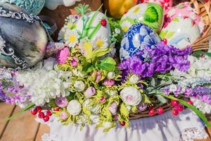 Festive easter background. Colorful painted eggs in nest decorated with flowers photo