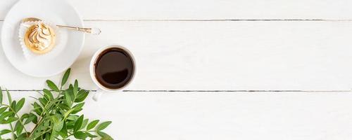 Cup of black coffee with mini cake on white table. The concept of breakfast, flat lay, top view. Banner photo