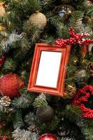 primer plano del árbol de navidad decorado con adornos de colores rojo, plateado y maqueta de marcos de fotos vacíos. concepto festivo de tarjeta de felicitación de invierno