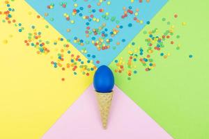 Pop colors. Festive multicolored background with bright sugar sprinkles scattered on paper, wafer cone end easter egg. photo