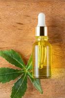 Cannabis leaf Serum, cosmetics, hemp oil. Bottle or vial with a dropper and hemp leaf on wooden board. Natural cosmetics concept photo