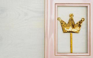 Pink photofrme with golden sequins crown on white wooden backgound. Minimal flat lay with copy space photo