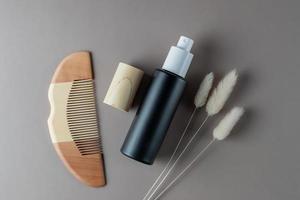 Products for daily hair care. Wooden Comb and hair smoothing spay on broven background. top view photo