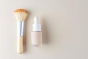 make up liquid foundation with bamboo brush on pastel background. Skin tone corrector in unbranded dropper bottle. photo