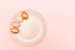 Top view of pink, white and golden decorated eeaster eggs on pink plate on pink background. Trendy holiday backdrop. photo