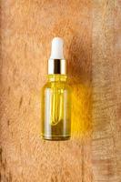 Skin care essence oil dropper glass bottle on wooden background. Hydrating serum, vitamin for face skin. Aesthetic, minimalism. photo