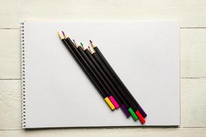 lápices de colores sobre papel de álbum blanco en blanco. vista superior. útiles escolares y de oficina foto
