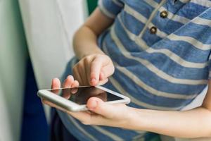 Close up of a kid hands using mobile smart phone. Selective focus photo