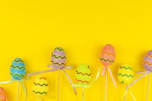 huevos de pascua multicolores en palos sobre fondo amarillo. tarjeta de felicitación festiva de vacaciones de pascua con espacio de copia foto