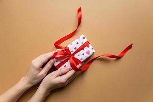 Top view of female hands holding present box package over flat lay background photo