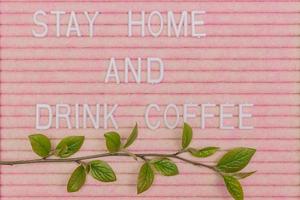 Lettreing booard with quote stay home and drink coffee decorated with spring branch with green fresh leaves. Spring motivation background. photo