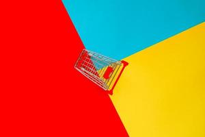 Top view of empty shopping trolley on colorful bright background. Concept of shopping and consumerism. Minimal flat lay. photo