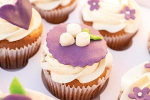 Closeup photo of colorful cupcakes with sugar icing in paper box.